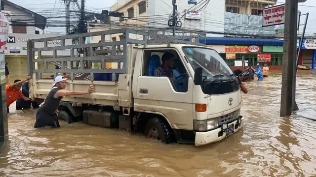 တာချီလိတ်မြို့၊ ရေကြီးရေလျှံနေတဲ့ လမ်းပေါ်မှာ ကားတွန်းနေကြတဲ့ အမျိုးသားတွေ