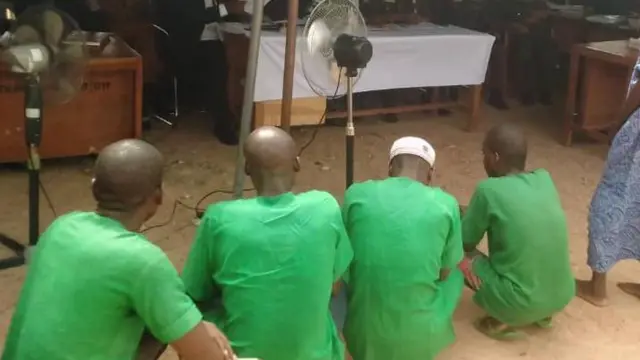 Wasu fursunoni uku sun juya bayansu a tsugune sanye da korayen kayan gidan yari