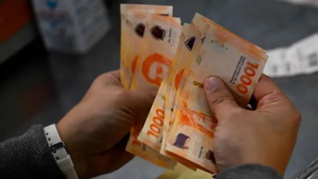 Mãos contando dinheiro (pesos argentinos)