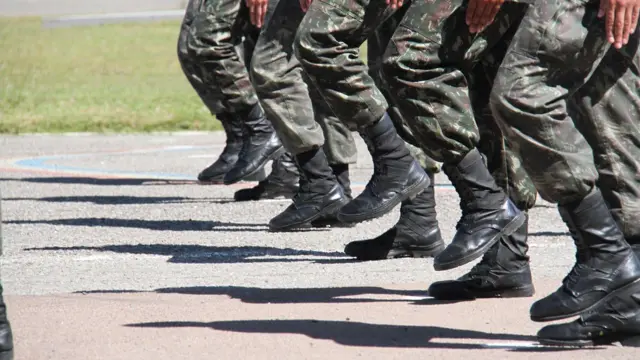 Fotografia colorida mostra pernas de soldados em marcha
