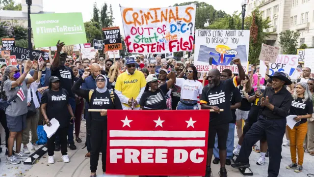 Manifestantes vestidos com camisetas prestas em que se lê "Freedom DC" seguram cartazes pedindo a saída de Trump e a liberdade para a capital dos EUA. 