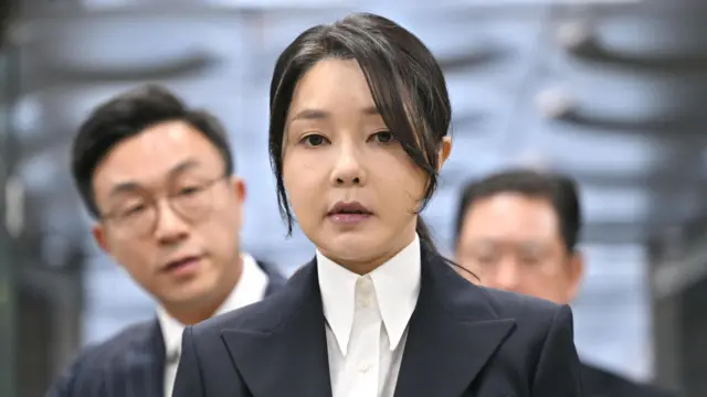 Kim Keon Hee chega ao Tribunal Distrital Central de Seul, na Coreia do Sul, para comparecer a uma audiência para analisar seu mandado de prisão. Sua expressão facial é solene e ela veste uma camisa branca e um terno preto.