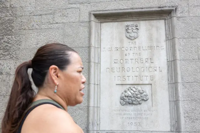 La Madre Mohawk Kwetiio pasa frente a la placa de dedicación del ala McConnell del Instituto-Hospital Neurológico de Montreal el 17 de julio de 2024, en Montreal, Canadá.(Photo by Alexis Aubin / AFP) (Photo by ALEXIS AUBIN/AFP via Getty Images)