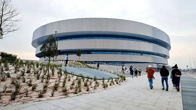 Хоккейная арена в Милане при дневном свете. Рядом идут люди