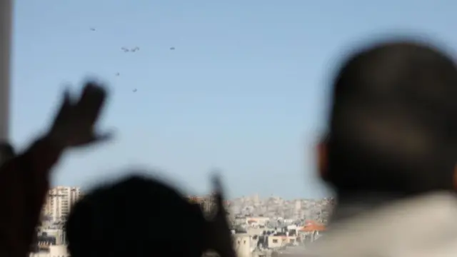 Niños viendo como caen paquetes de ayuda sobre la ciudad de Gaza
