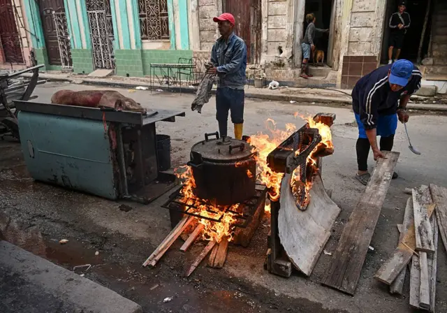 Unas personas cocinan con leña en la calle en La Habana.