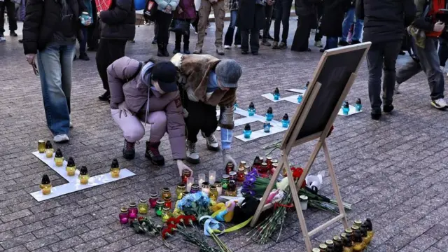 Des personnes allument des bougies lors d'un rassemblement commémoratif pour marquer l'anniversaire du bombardement du théâtre de Mariupol en 2022, devant l'Opéra, le 16 mars 2025 à Kiev, en Ukraine.