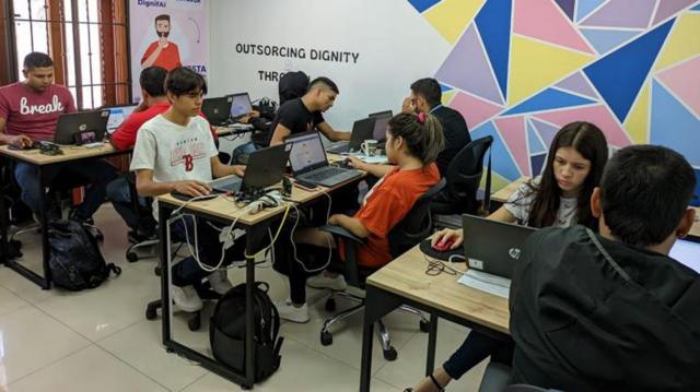 Vários jovens sentadosaposta mais de 2 5 golstrês mesas com laptops, com feições sérias