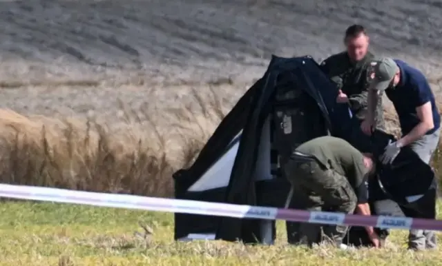 Військові у зеленому полі оглядають елементи дрона