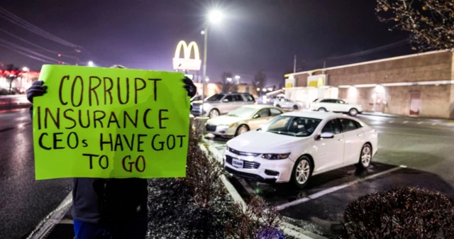 Mangione'nin tutuklandığı yere gelen kişi "Yolsuzluk yapan sigorta şirketi yöneticileri gitmeli" yazılı pankart tutuyor