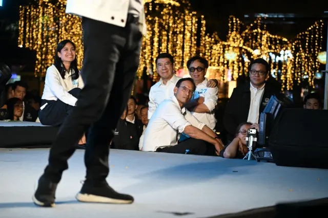 แกนนำ ปชป. รวมถึงสาทิตย์ (ยืนกอดอก) ร่วมฟังการเปิดปราศรัยใน กทม. ของหัวหน้าพรรค เมื่อ 11 ม.ค.