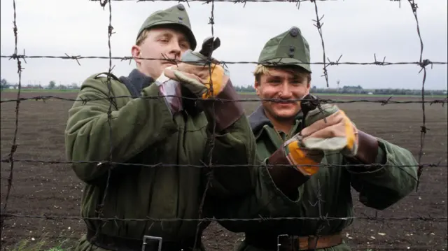 Két katona éppen átvágja a határt övező kerítést.