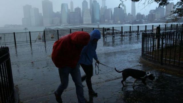 Gente en la calle caminando bajo la lluvia durante el huracán Sandy