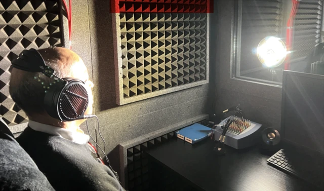 Pallab sentado dentro de una cabina con unos audífonos y al frente el foco de una luz