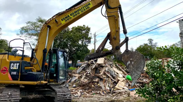 Retroescavadeira recolhendo os pedaçospixbet saque pixconstrução destruída