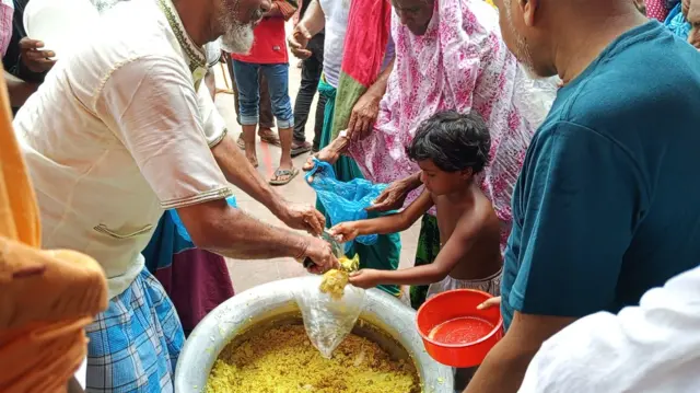 মাজারে একজন শিশুকে খাবার দেওয়া হচ্ছে