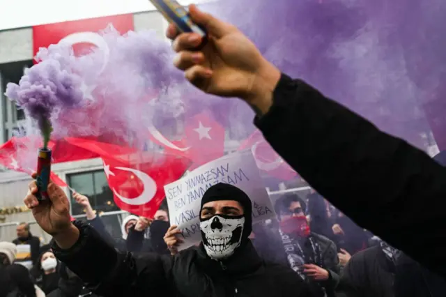 Para pengunjuk rasa memegang suar asap ungu selama unjuk rasa menentang penangkapan Wali Kota Istanbul, Ekrem Imamoglu.