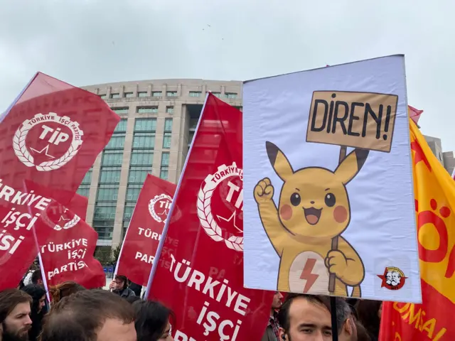 Öğrencilerin taşıdığı bir pankartta Pikaçu karakteri "Diren!" yazılı pankart tutuyor.