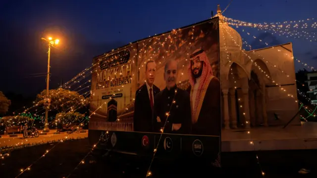 Pôster decorado para marcar o Pacto de Meca ilustra os líderes da Turquia, Paquistão e Arábia Saudita