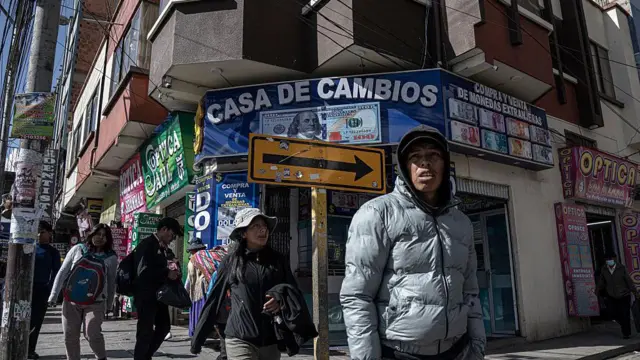 Personas caminan frente a casas de cambio en el centro de El Alto, Bolivia, el jueves 14 de agosto de 2025. 