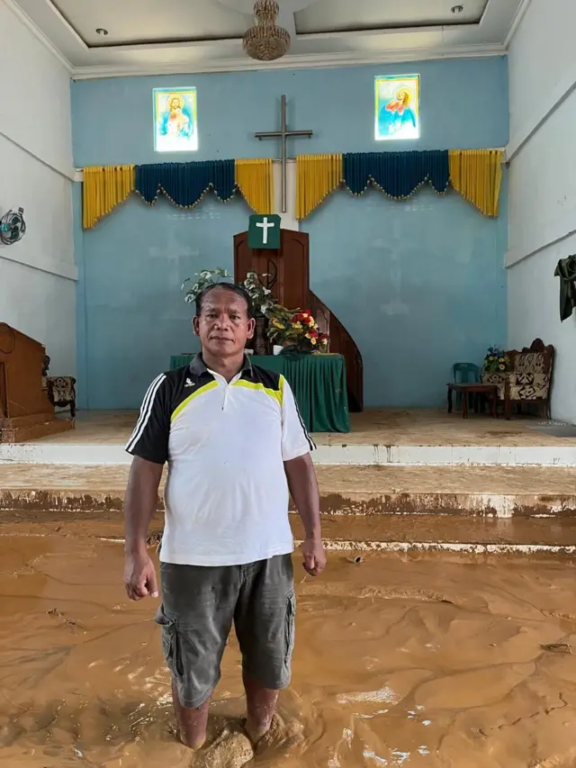 Pendeta Paten Sidabutar membelakangi altar gereja. Ia berdiri di lautan lumpur yang merebak ke seluruh bangunan gereja.