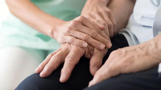 يد شابة تمسك بيد مسنّ 