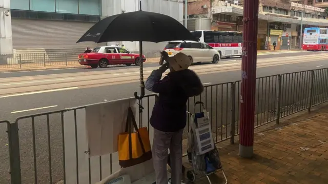 ایک عورت ایک بڑی عمارت کے سامنے مظاہرہ کرتے ہوئے پیچھے سے دکھائی دے رہی ہیں