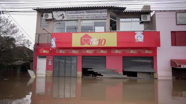 Foto colorida mostra sobrado comercial com a porta estouradabrabet oficialuma rua alagada