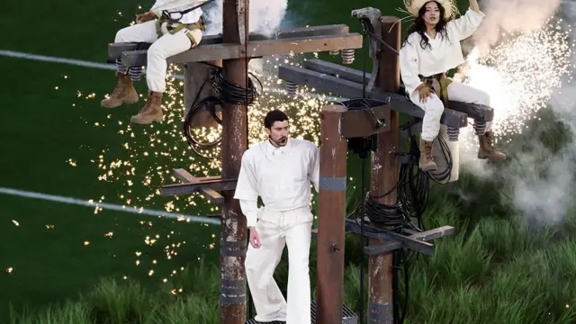 bad bunny recreó el maltrecho tendido eléctrico de puerto rico durante su espectáculo en el show de medio tiempo del super bowl. En la foto se le ve cantando en un poste de electricidad.