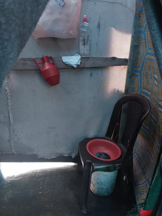 كرسي بلاستيكي مثقوب خلف ساتر قماشي