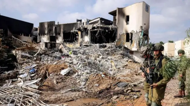 હમાસના બંદૂકધારીઓ દ્વારા આગના હવાલે કરવામાં આવેલા પોલીસ સ્ટેશન બહાર પહેરો ભરતા ઇઝરાયેલી સૈનિકો