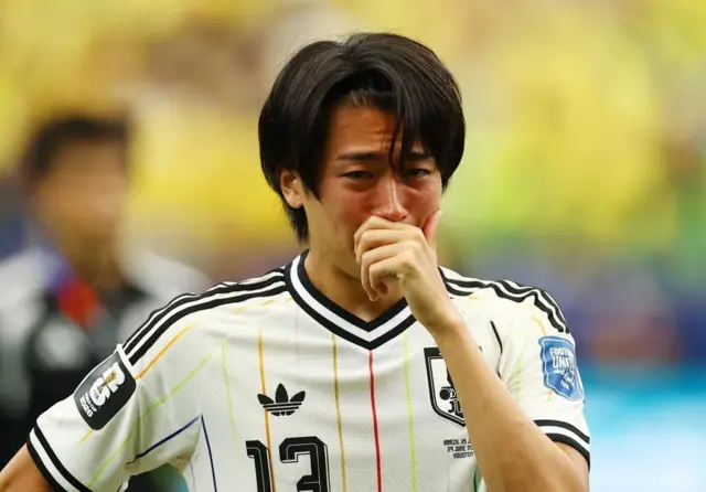 白色ユニホームの選手が顔を赤くして、右手を口に当てている