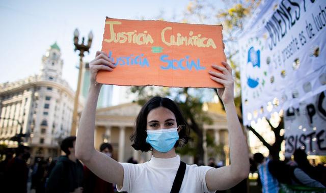Una joven en Argentina con un cartel que dice "justicia climática es igual a justicia social"