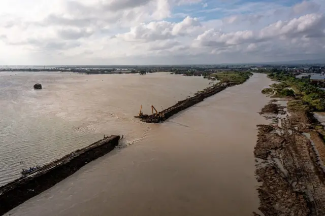 Foto udara pekerja mengoperasikan mesin pengeruk (excavator) guna menutup tanggul Sungai Wulan yang jebol di Desa Ketanjung, Kecamatan Karanganyar, Kabupaten Demak, Jawa Tengah, Senin (18/3/2024).