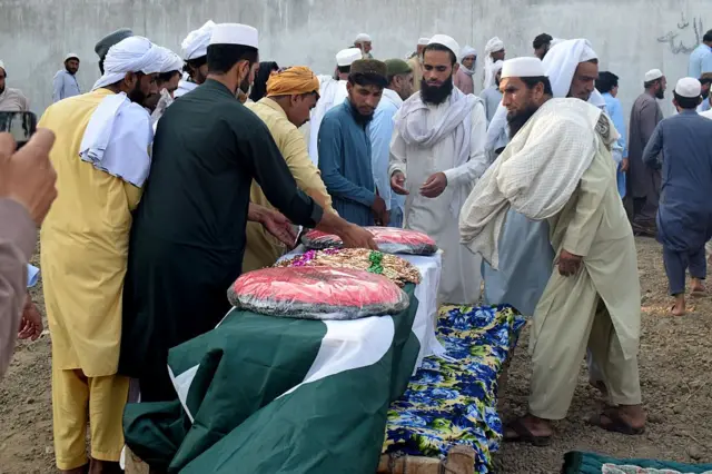 لوگ دھماکے میں مارے جانے والے پولیس کانسٹیبل راحات اللہ کے تابوت پر پھول رکھ رہے ہیں۔