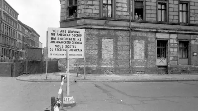 Una calle en Berlín con una valla que avisa en cuatro idiomas que se está abandondando el sector estadounidense. Muro de Berlín