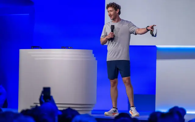 Mark Zuckerberg en un escenario vistiendo una camiseta, una pantaloneta y tenis.