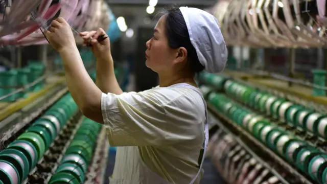 Una mujer trabaja junto a bobinas de seda en una fábrica de Fuyang, en la provincia china de Anhui.