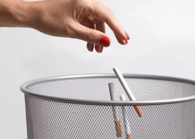 Main jetant des cigarettes dans une poubelle