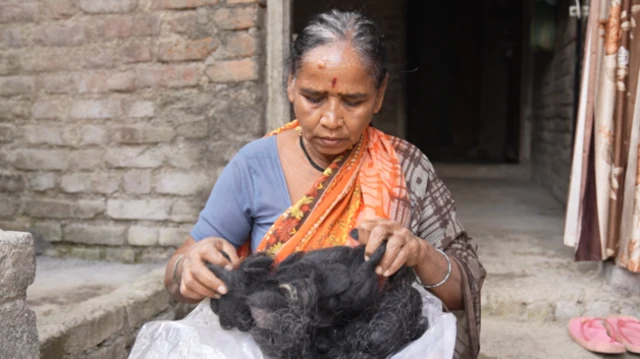 Žena sedi i drži opalu kosu u ruci