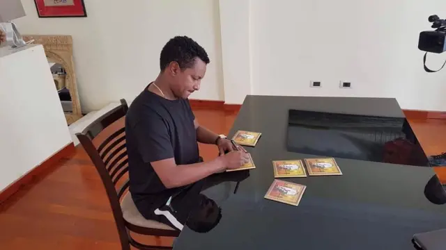 ቴዎድሮስ ካሳሁን ኢትዮጵያ የሰኘ አልበሙ ላይ ፊርማውን እያኖረ