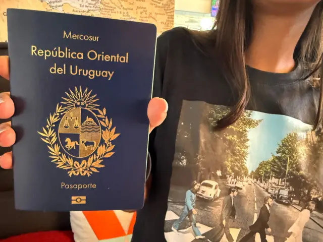 Una mujer sostiene un pasaporte uruguayo