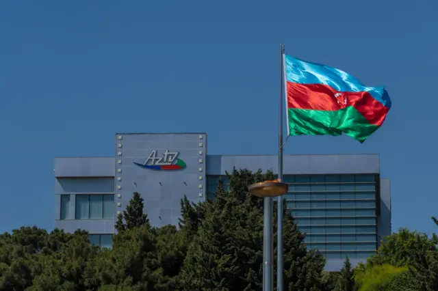 نمای دور از ساختمان «آذ تیوی»، و مقابل آن پرچم جمهوری آذربایجان در اهتزاز
