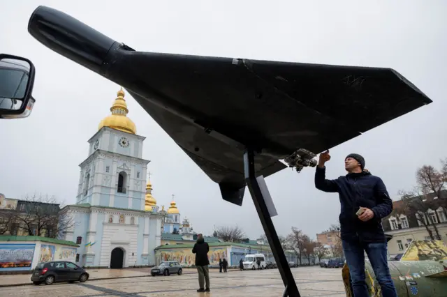 Um morador toca um drone russo-iraniano Shahed-136 (Geran-2) instalado em frente à catedral de São Miguel como parte de uma exposição de veículos e armas militares russas destruídas, em meio ao ataque da Rússia à Ucrânia, em Kiev, na Ucrânia, em 26 de novembro de 2025.
