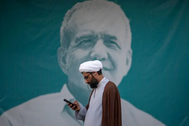 یک روحانی در مقابل عکس پزشکیان