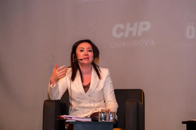 Beyaz ceketli bir kadın konuşuyor