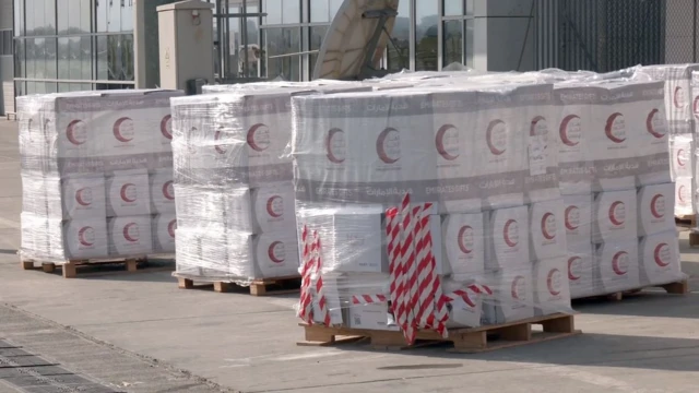 تصویر محموله کمک امارات متحده عربی در میدان هوایی و محموله‌ها نشان هلال احمر امارات را دارند. 