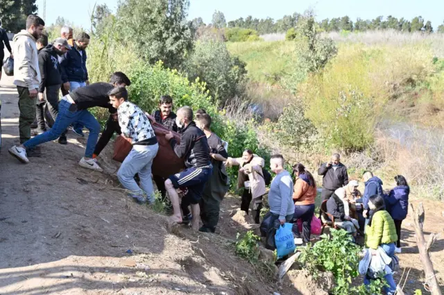 Kaçan siviller, yerleşimin olmadığı bir kırsalda, bir yamaçtan çıkıyor, 11 Mart 2025.