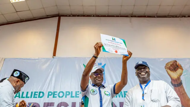 Man wear white holding up certificate