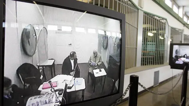 Giuseppe "Pippo" Calo (kanan di layar) muncul melalui tautan video dari sebuah penjara di Italia tengah, selama persidangan tersangka pembunuh Roberto Calvi, yang dikenal sebagai "Bankir Tuhan", di bunker gedung pengadilan di pinggiran Roma pada 23 November 2005.